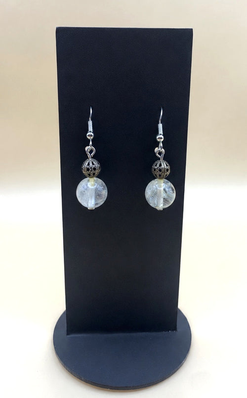 Moonlit filigree crystal drop earrings on a black display stand